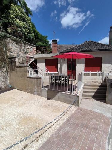 Un patio con una mesa y una sombrilla roja. en Le petit gîte de la butte, en Gourdon-en-quercy