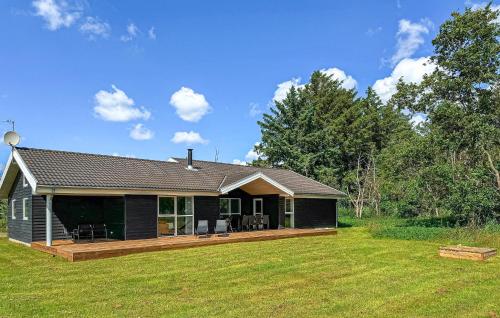 a black house with a deck in a yard at Holiday Home Nørtvedvej Strandby Denm in Strandby