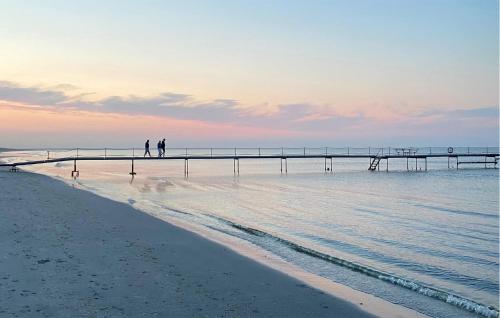 two people walking on the beach near a pier at Holiday Home Nørtvedvej Strandby Denm in Strandby