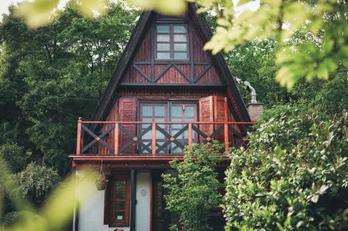a red house with a balcony on top of it at Erdő Lelke Vendégház: mesebeli, erdőszéli faház panorámával in Nagymaros