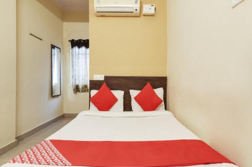 a bedroom with a bed with red pillows at Hotel O Sai Pariwar in Vidya Nagar