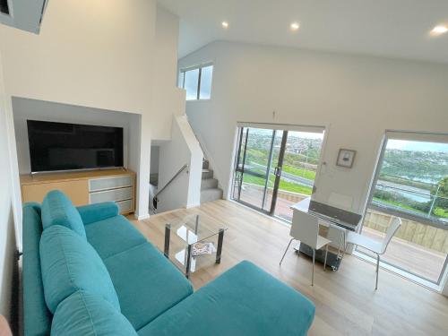 a living room with a blue couch and a tv at Basin View in Auckland