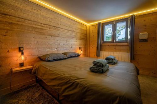 a bedroom with a large bed in a wooden wall at Pétillant Chalet aux 3 étangs avec SPA, Sauna et Véranda in Gerbépal