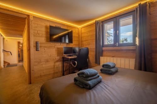 a bedroom with a bed and a desk and a television at Pétillant Chalet aux 3 étangs avec SPA, Sauna et Véranda in Gerbépal