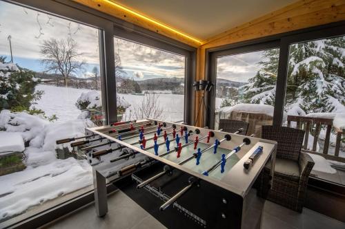 a foosball table in a living room with snow at Pétillant Chalet aux 3 étangs avec SPA, Sauna et Véranda in Gerbépal