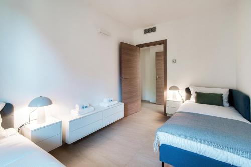 a white bedroom with two beds and a mirror at Lario Suite Apartments by Quokka 360 - With parking Next to Como City in Como
