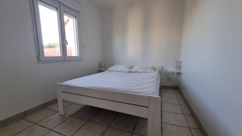 un lit blanc dans une chambre avec une fenêtre dans l'établissement Le Mas de la Tortue (Plain Pied), à Caromb