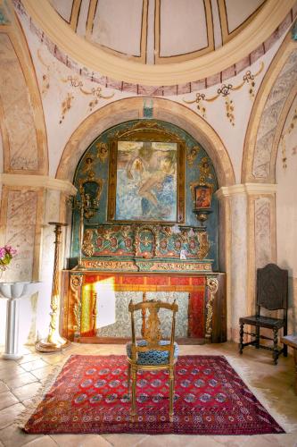 a room with a fireplace with a chair and a painting at Hotel de Charme Capela das Artes in Armação de Pêra