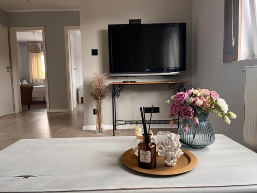 a living room with a table with flowers and a tv at CHILLIapartamenty - Dom w Grzybowie-W Brzozach in Grzybowo