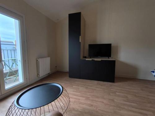 a living room with a flat screen tv and a table at Welcome Home Parking, terrasse in Châteauroux