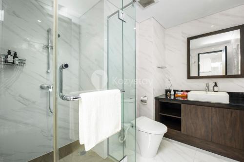 a bathroom with a shower and a toilet and a sink at Carrara by Kozystay - BSD in Tangerang