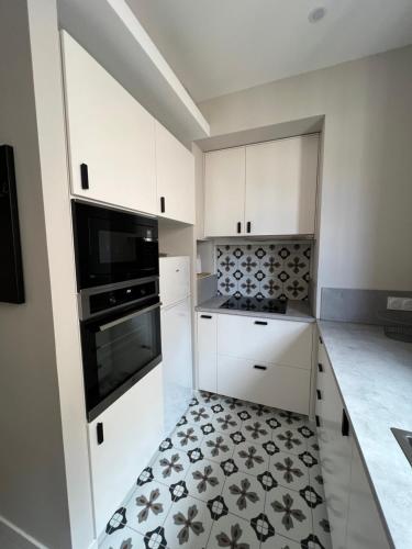 - une cuisine avec des placards blancs et du carrelage noir et blanc dans l'établissement Très bel appartement mourillon T2, à Toulon