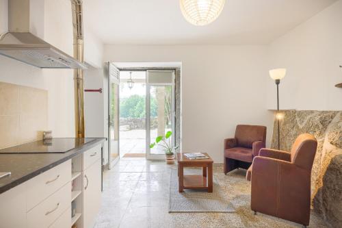 a kitchen and living room with a couch and a chair at Cosy apartment at Portuguese Quinta in Casal Diz