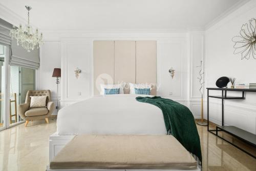 a white bedroom with a large bed and a chair at Askara by Kozystay - Ciumbuleuit in Bandung