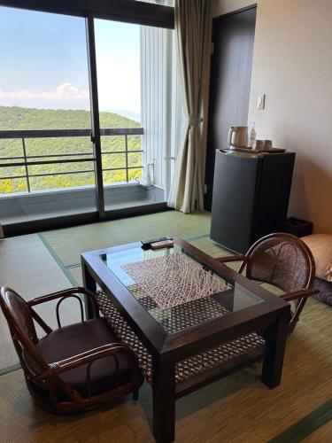 a living room with a coffee table and two chairs at Hotel Bokaiso in Takamatsu