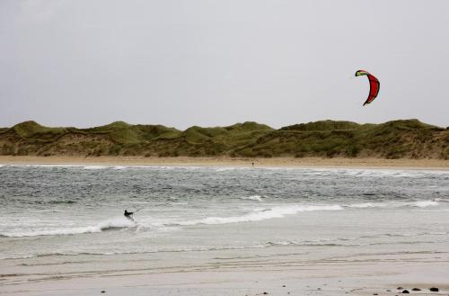 a person kite surfing in the ocean on the beach at Matthews Cottage Doonbeg sleeps 6 by Trident Holiday Homes in Doonbeg