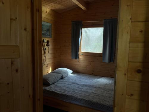 a small bedroom with a bed in a log cabin at Tõhela Järve Puhkeküla in Männikuste