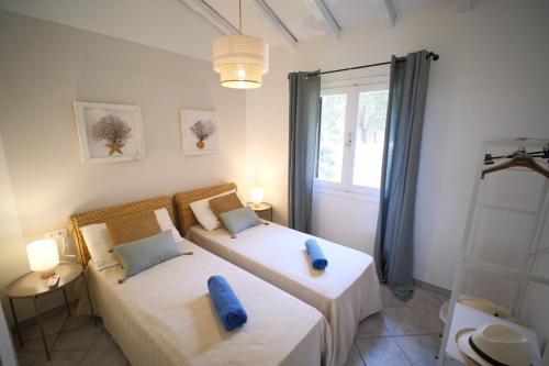 two beds in a bedroom with two blue pillows at Porto Rotondo home with Pool access & Sea Views in Porto Rotondo