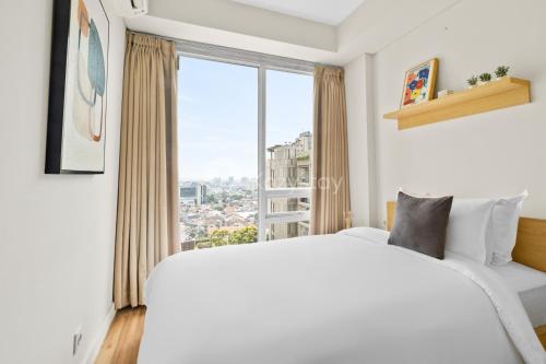 a bedroom with a large white bed and a large window at Karaton by Kozystay - Paskal in Bandung