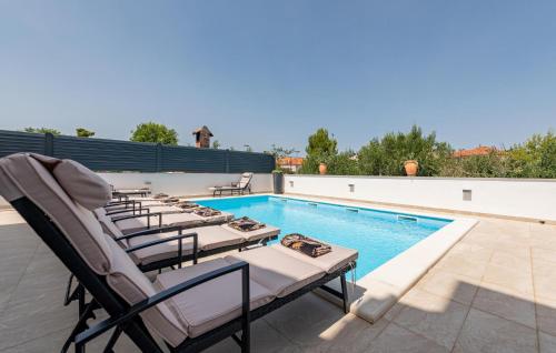 a row of chaise lounge chairs next to a swimming pool at Amazing Home In Zadar With Wifi in Zadar