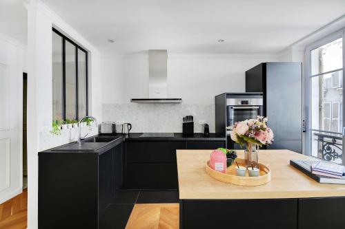 une cuisine avec des armoires noires et une table fleurie dans l'établissement Trendy apartment - 2BR-4P - Saintonge-Le Marais, à Paris