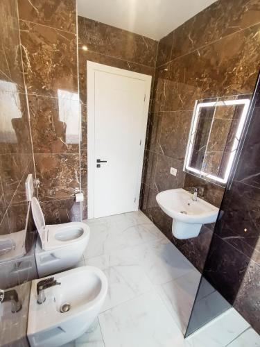 a bathroom with a toilet and a sink and a mirror at Bulevardi Blu 1 in Kamëz