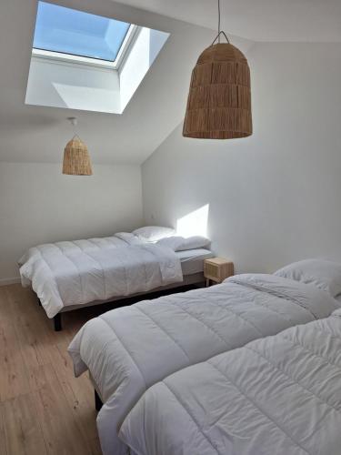 two beds in a white room with a window at Au Cœur Des Champs in La Petite-Boissière