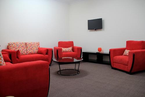 a waiting room with two red chairs and a tv at Abu Mazen Hotel in Khirbat an Naşārá