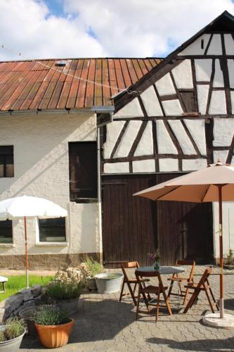 a building with two tables and an umbrella at Landhof PAU in Mappershain