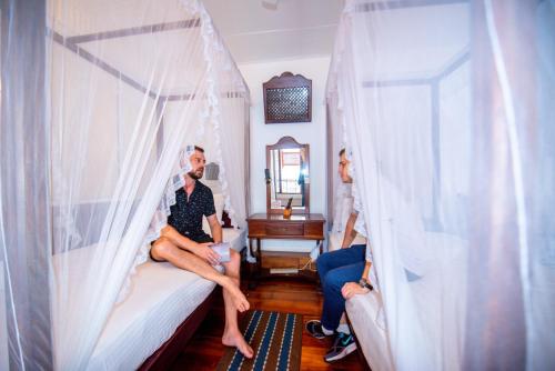 a man and two women sitting on a bed at Cara Galle Fort in Galle