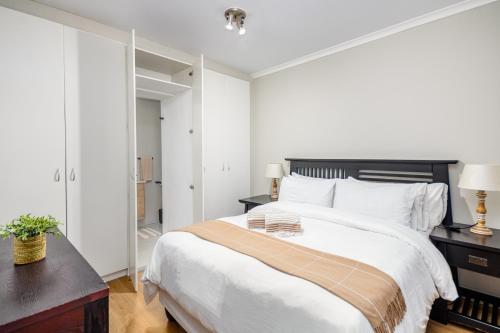 a white bedroom with a large bed and a mirror at Atlantic Haven in Bloubergstrand
