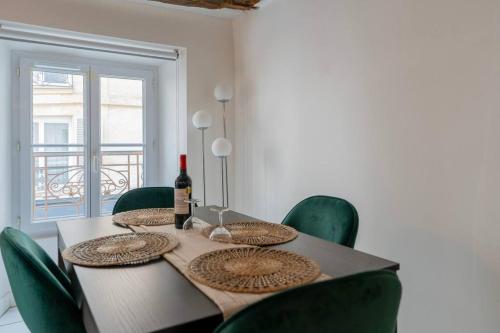 - une table à manger avec des chaises vertes et une bouteille de vin dans l'établissement Central Apartment Paris Opera Garnier, à Paris