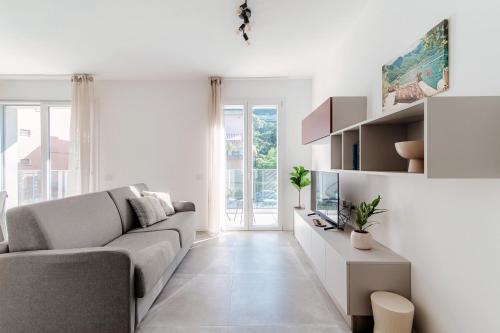 a white living room with a couch and a tv at Lario Suite Apartments by Quokka 360 - Close to Como Downtown in Como