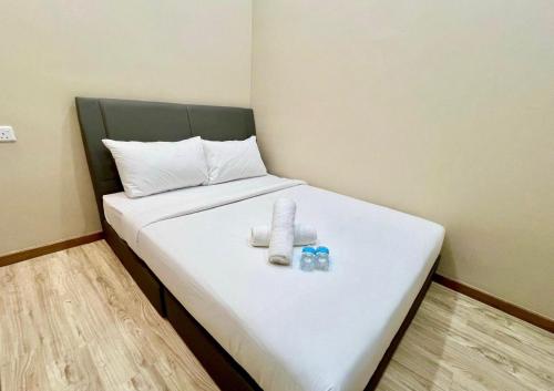 a bed with two towels and two bottles on it at Infinity Hotel Iskandar Puteri in Iskandar Puteri
