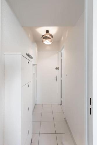 - un couloir avec des murs blancs et du carrelage blanc dans l'établissement T2 proche mer et commerces, à Palavas-les-Flots