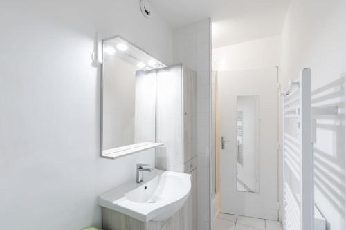 une salle de bain blanche avec un lavabo et un miroir dans l'établissement T2 proche mer et commerces, à Palavas-les-Flots
