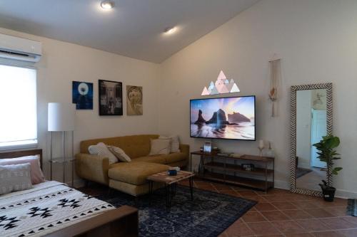 a living room with a couch and a tv on the wall at Lofty Dreams B&B, studio near Disney & Universal in Orlando