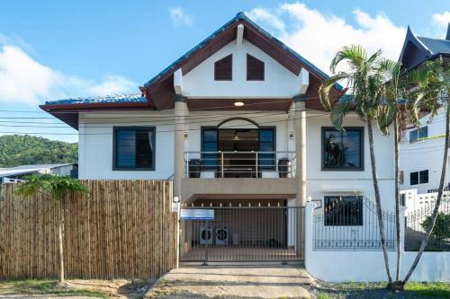 a white house with a fence and a palm tree at Golden Sands Villa only 15 minutes walk to beach in Ban Lum Fuang