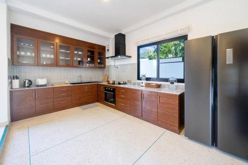 a kitchen with wooden cabinets and a large window at Golden Sands Villa only 15 minutes walk to beach in Ban Lum Fuang