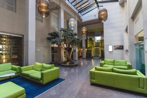 a lobby with green couches and a tree in the middle at Mercure Nantes Centre Grand Hotel in Nantes