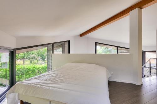 une chambre avec un lit et une grande fenêtre dans l'établissement 950m plage - Maison architecte 4 adultes - 2enfants, à Andernos-les-Bains