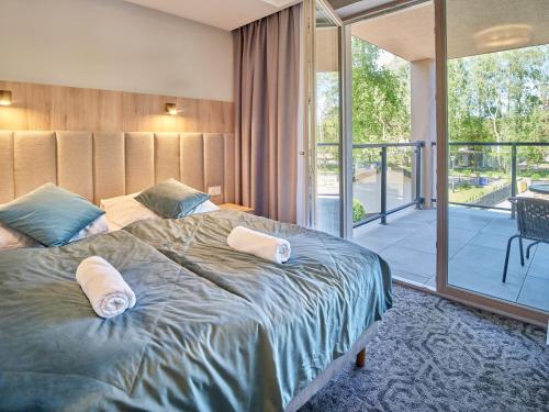 a bedroom with a large bed and a balcony at Rezydencja AMBRE in Łeba