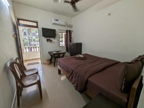 a bedroom with a bed and a chair and a television at Vinsons Cottages in Colva