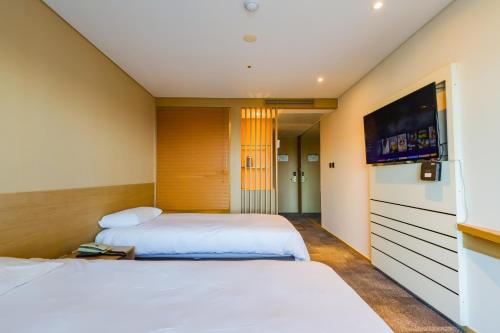 two beds in a hotel room with a tv at From H The Best Hotel Jeju Seongsan in Seogwipo