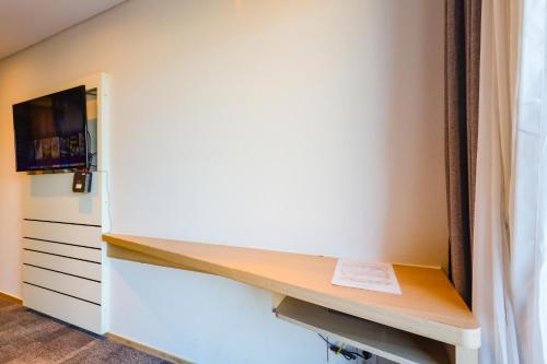 a room with a desk and a tv on a wall at From H The Best Hotel Jeju Seongsan in Seogwipo