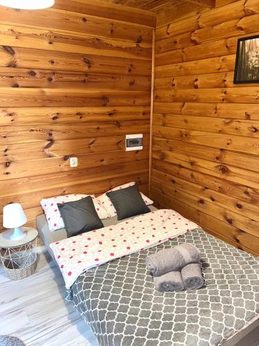 a bedroom with a bed in a wooden wall at Domek na wzgórzu in Tumiany