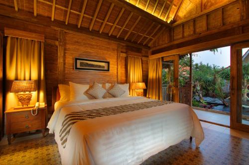 a bedroom with a large white bed and a window at Suarti Boutique Village in Ubud