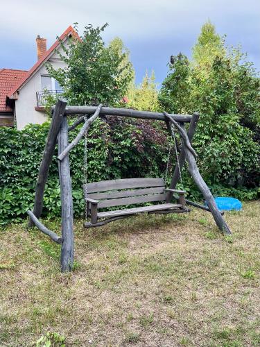 a wooden swing in a yard with a blue frisbee at Domek na wzgórzu in Tumiany