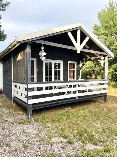 a small black house with a white porch at Domek na wzgórzu in Tumiany