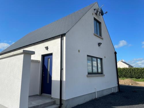 un pequeño edificio blanco con una puerta azul en Alderton Guesthouse, en Carlow